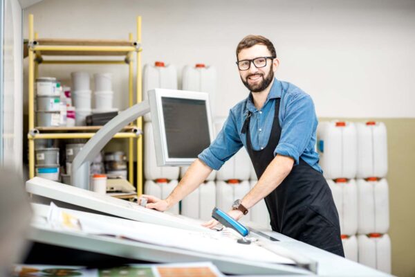 Portrait of a male worker at the printing manufacturing Portrait of a male worker standing near the operating desk of the printing manufacturing